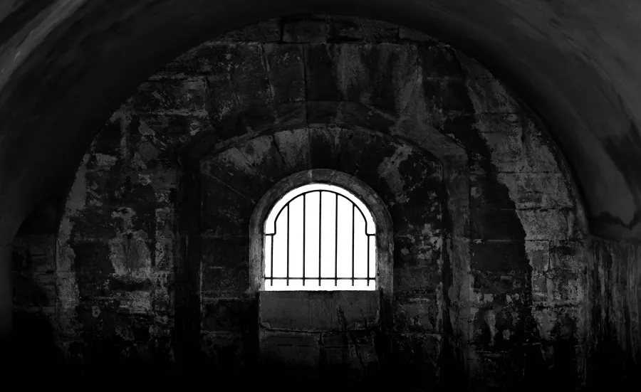 Dark prison cell with barred window