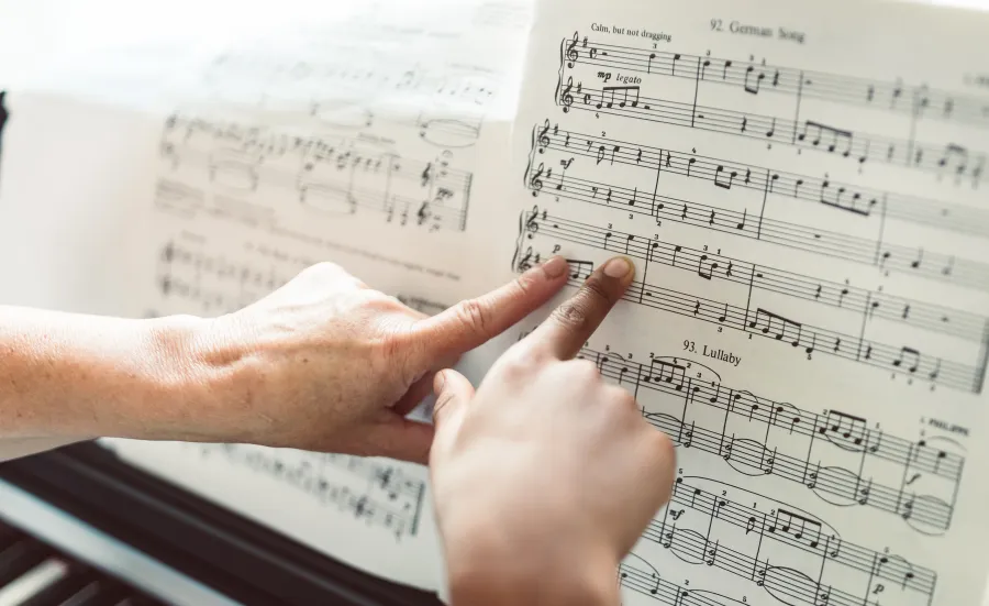 2 fingers pointing at sheet music on a piano