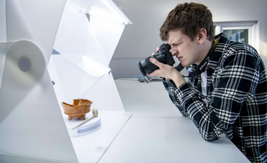 A student photographing small archaeological objects in a dedicated photography studio.