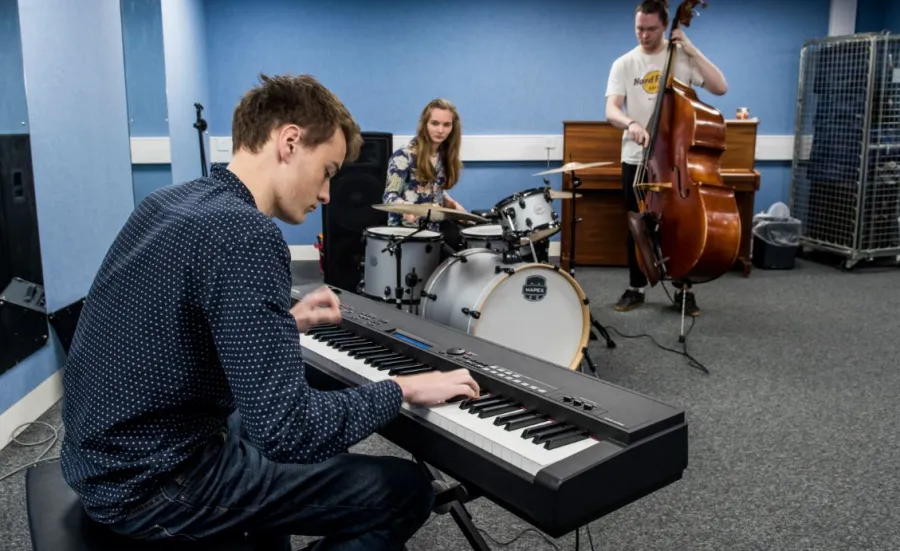 A group of three students practising in a music ensemble room