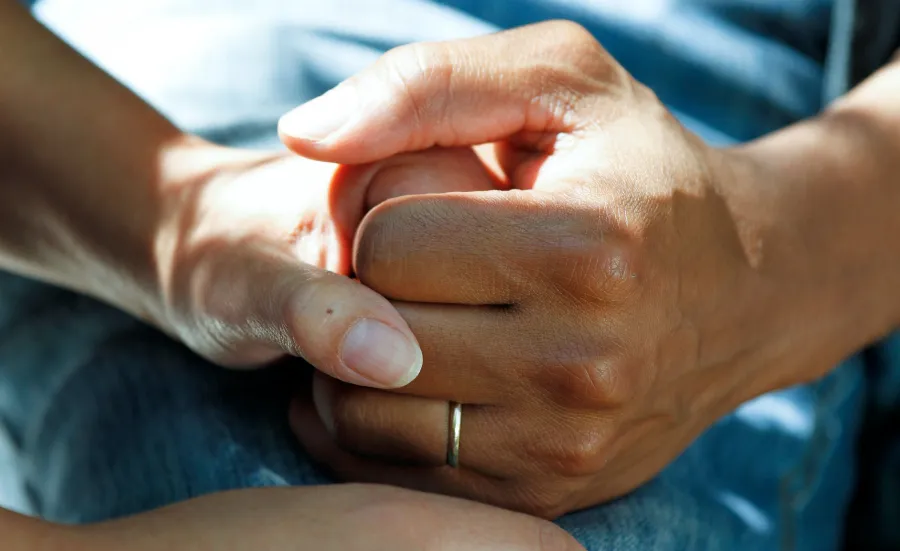 Comforting hands on a hospital bed