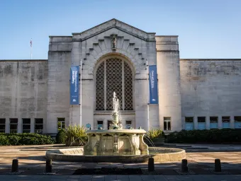 A grand building with classic architectural elements such as a stone façade and arched windows and a fountain gushing in front, Southampton's City Art Gallery.