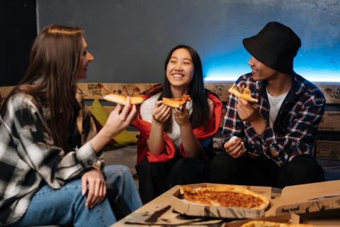 Three teenagers eating takeaway pizza