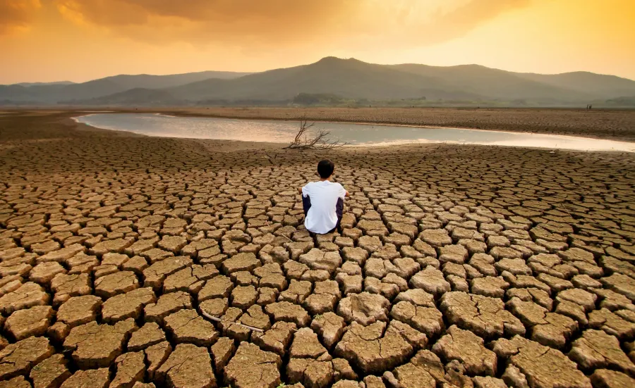 A man sit on dry land in an empty lake
